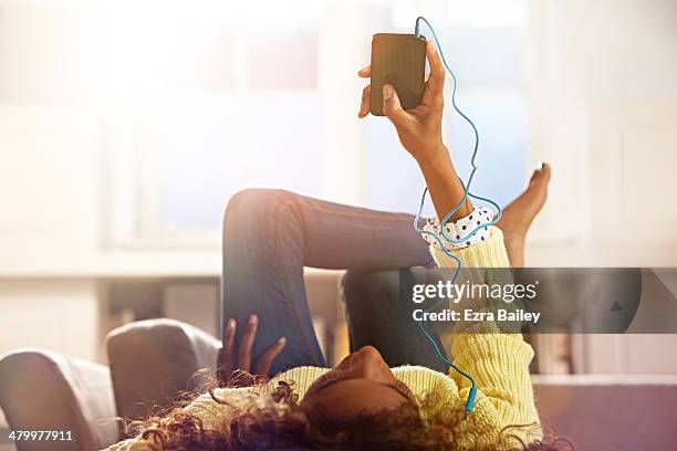 woman relaxing at home listening to her phone. - auriculares equipo de música fotografías e imágenes de stock