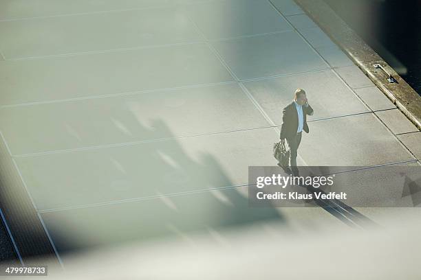 businessman walking with phone in low light - answering stockfoto's en -beelden