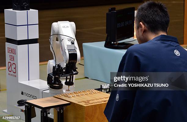 Robot arm , developed by Jpanese auto parts maker Denso and operated by computer game software YaneuraOu, plays against professional shogi, or...