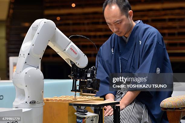 Robot arm , developed by Japanese auto parts maker Denso and operated by computer game software YaneuraOu, plays against professional shogi, or...