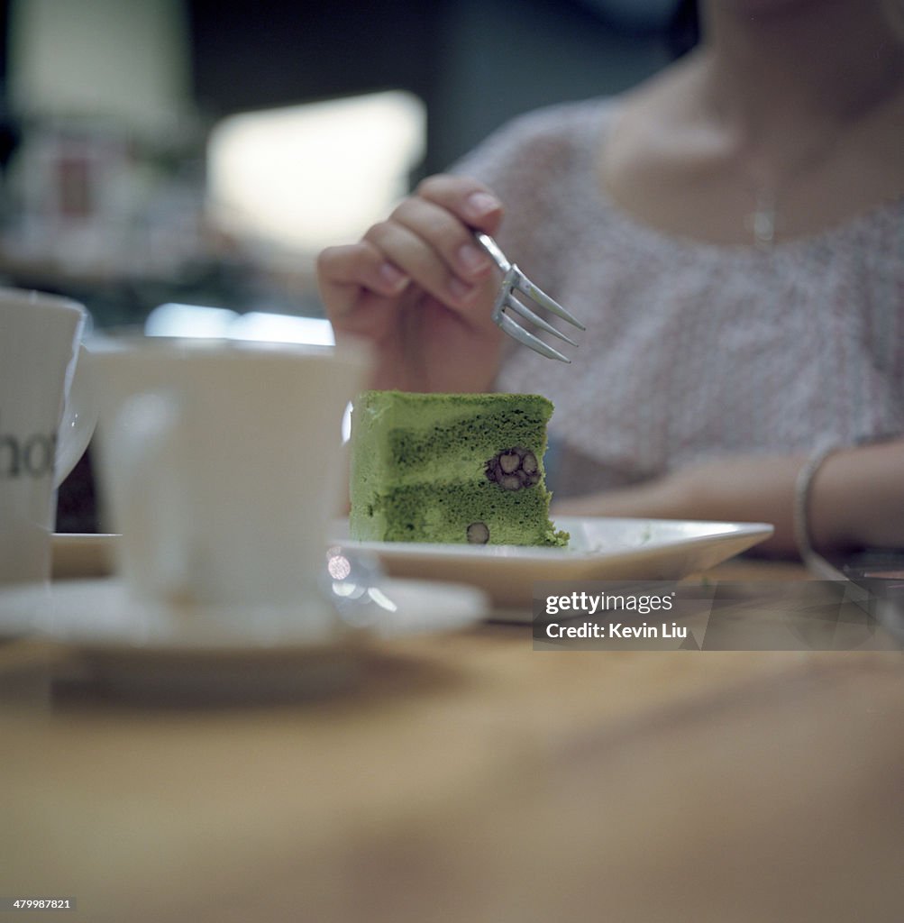A slice of green tea cake in front of a woman