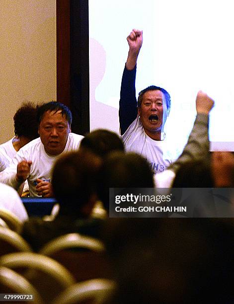 Angry Chinese relatives of passengers from the missing Malaysia Airlines flight MH370 raise their arms in protest during a press conference at the...