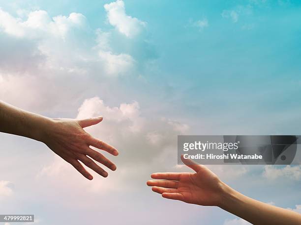 two hands seem to reach together in the sky - out of reach stock pictures, royalty-free photos & images