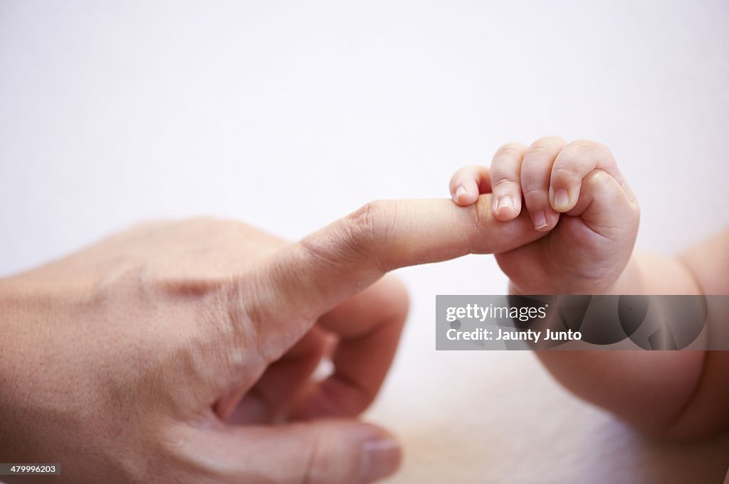 Baby's small hand holding father's finger