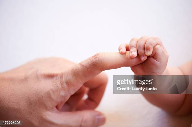 baby's small hand holding father's finger