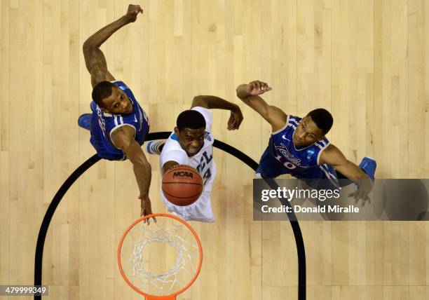 Jordan Adams of the UCLA Bruins lays up a shot in between Tim Peete and James Woodard of the Tulsa Golden Hurricane during the second round of the...