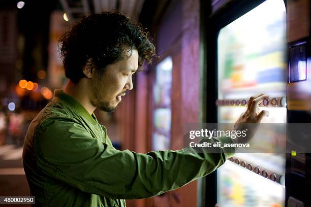 young japanese man using vending mashine in tokyo. - vending machine stock pictures, royalty-free photos & images