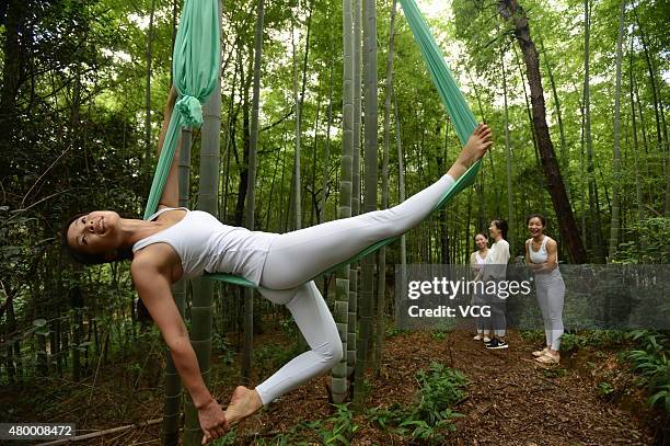 Woman practices yoga with hammock and hang in the air in the bamboo forest on July 4, 2015 in Changsha, China.