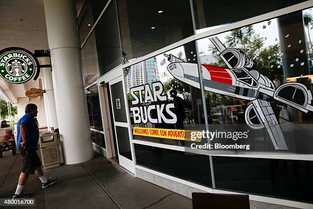 Man walks towards a Starbucks Corp. Store decorated with an illustration of a X-Wing fighter from the Star Wars franchise during the Comic-Con...