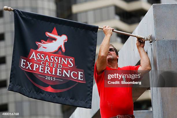 Worker hangs a flag for the Assassin's Creed Experience from UbiSoft Entertainment SA during the Comic-Con International convention preview in San...