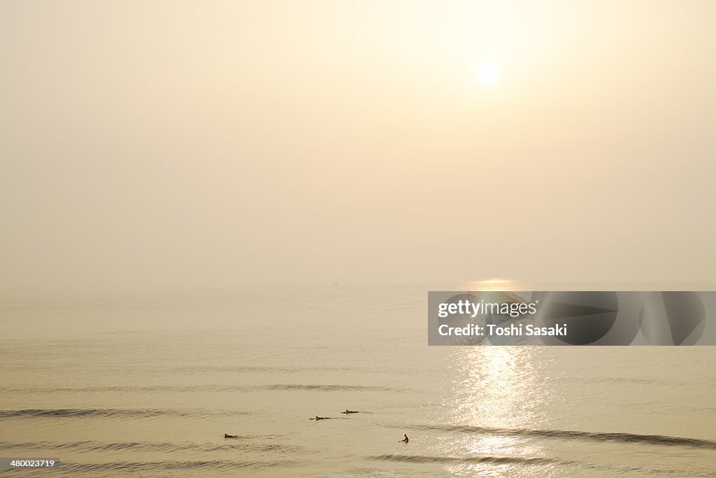 Overlooking surfers at glowing morning ocean
