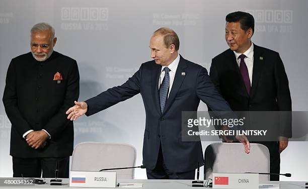 Russia's President Vladimir Putin welcomes Indian Prime Minister Narendra Modi and Chinese President Xi Jinping during a signing ceremony at the 7th...