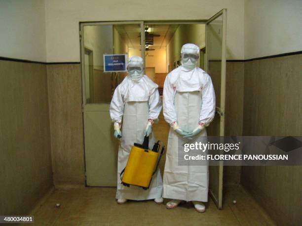 Two health workers, wearing protection outfits, leave the isolated area where people infected by the deadly Marburg virus are treated at the Americo...