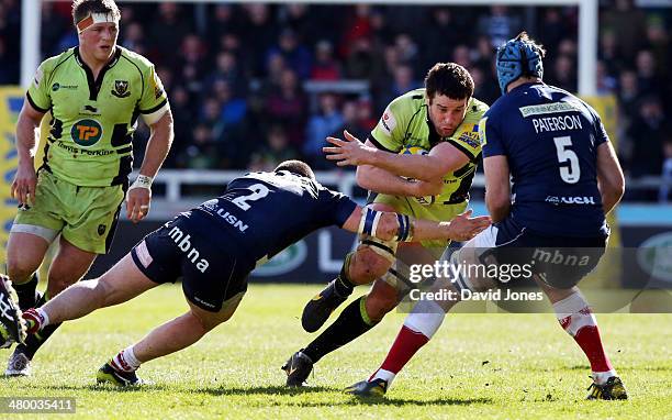 Calum Clark of Northampton Saints is tackled by Marc Jones and Michael Paterson of Sale Sharks during the Aviva Premiership match between Sale Sharks...