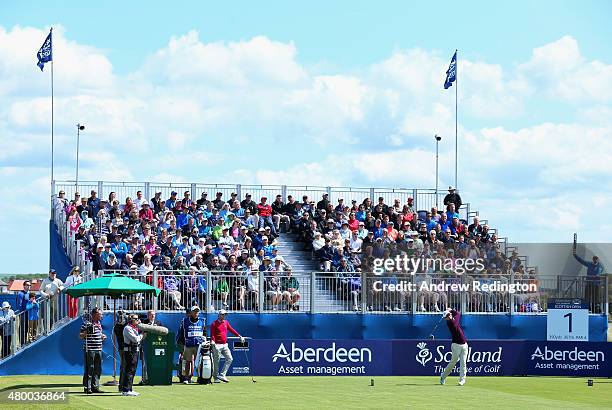 Justin Rose of England hits his tee shot on the first hole as a grandstand of fans look on during the first round of the Aberdeen Asset Management...