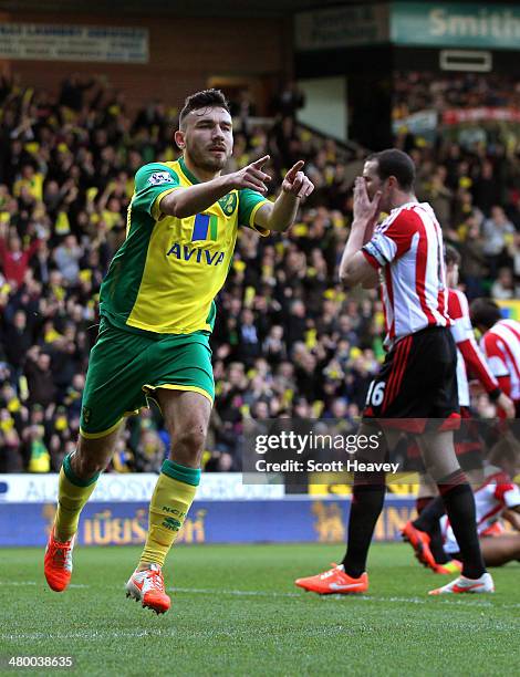 Robert Snodgrass of Norwich City celebrates scoring the opening goal as a dejected John O'Shea of Sunderland reacts during the Barclays Premier...