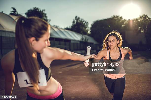 donne lo scambio di staffetta in una gara sportiva. - corsa a staffetta foto e immagini stock