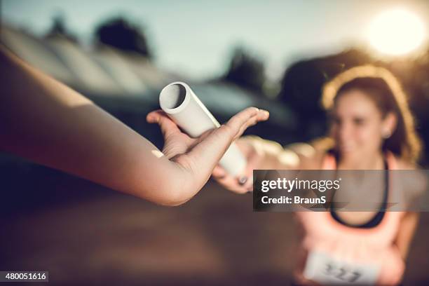 close up of exchanging relay baton on a sports race. - een pass geven stockfoto's en -beelden