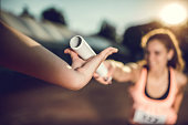 Close up of exchanging relay baton on a sports race.
