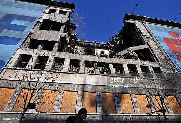 Woman walks on March 22, 2014 in front of the building of the former federal Interior Ministry in Belgrade, which was destroyed during the 1999 NATO...