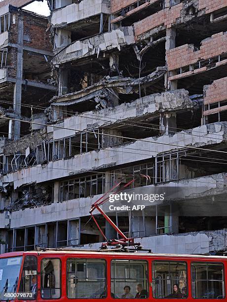 People ride a tram on March 22, 2014 past the building of the former federal Interior Ministry in Belgrade, which was destroyed during the 1999 NATO...