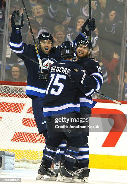 Jim Slater of the Winnipeg Jets celebrates a second period goal against the Carolina Hurricanes with teammates Matt Halischuk and Eric Tangradi at...