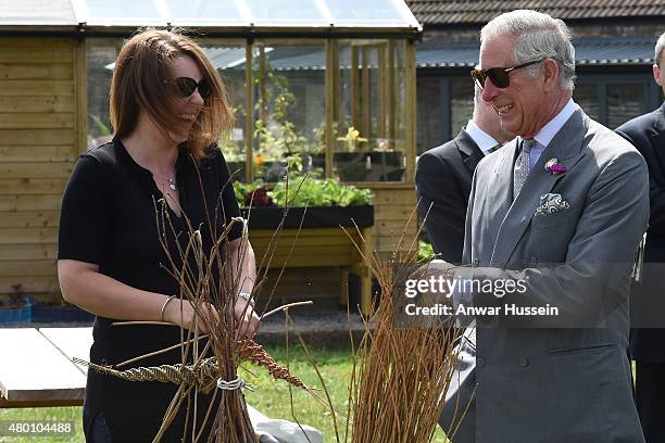 Prince Charles, Prince of Wales jokes with a willow weaver during a visit to 'Humble by Nature', a working organic farm run by broadcaster Kate...