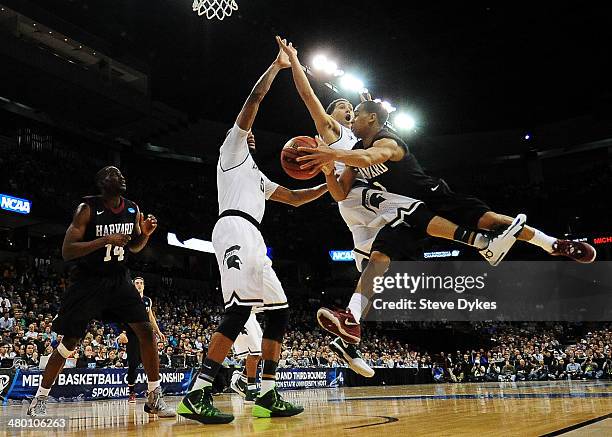 Siyani Chambers of the Harvard Crimson passes around Gary Harris and Adreian Payne of the Michigan State Spartans during the Third Round of the 2014...