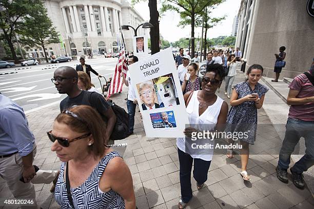 Woman holds a sign while marching to Trump Hotel during a protest against Donald Trump, candidate for the Republican Presidential ticket, after he...