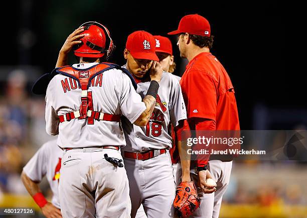 Carlos Martinez of the St Louis Cardinals is hugged by teammate Yadier Molina after being pulled from the game in the 8th inning by manager Mike...