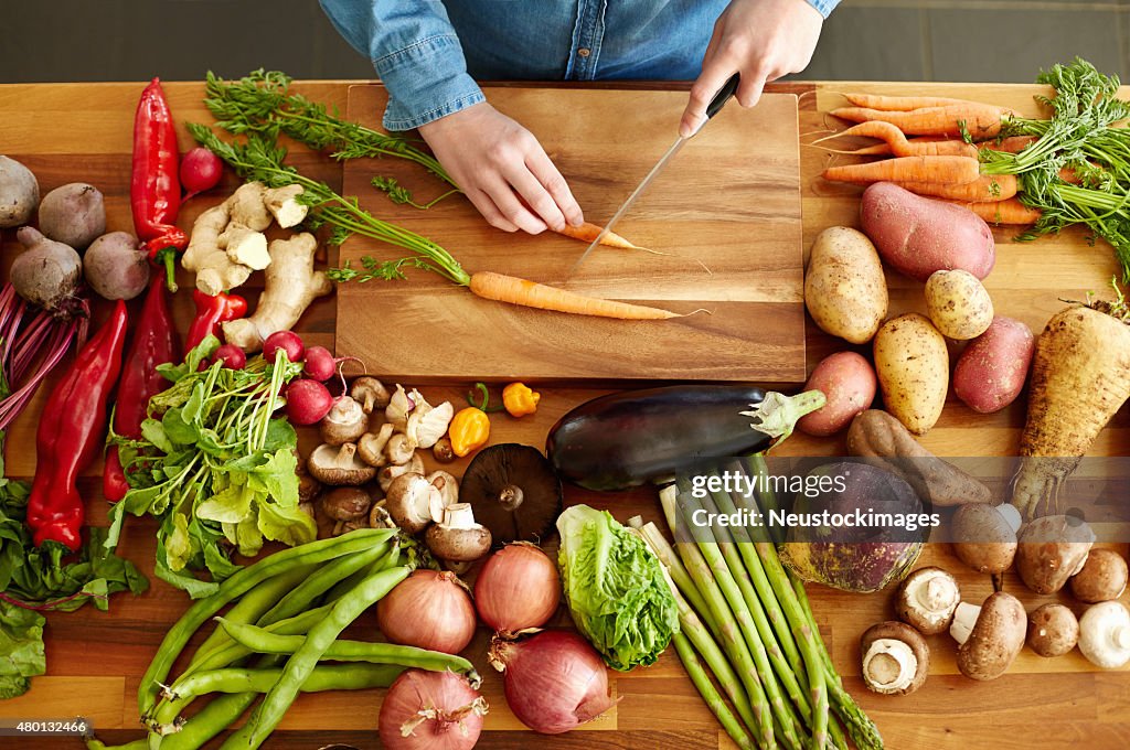 High angle view of hands cutting carrots by various vegetables