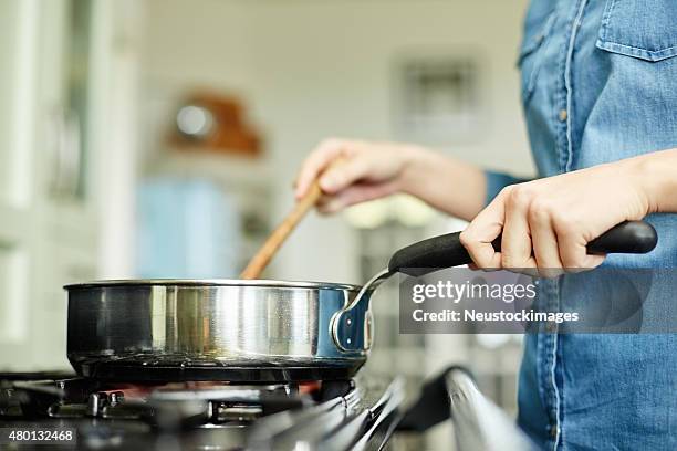 midsection image of woman cooking food in pan - gaskookplaat stockfoto's en -beelden