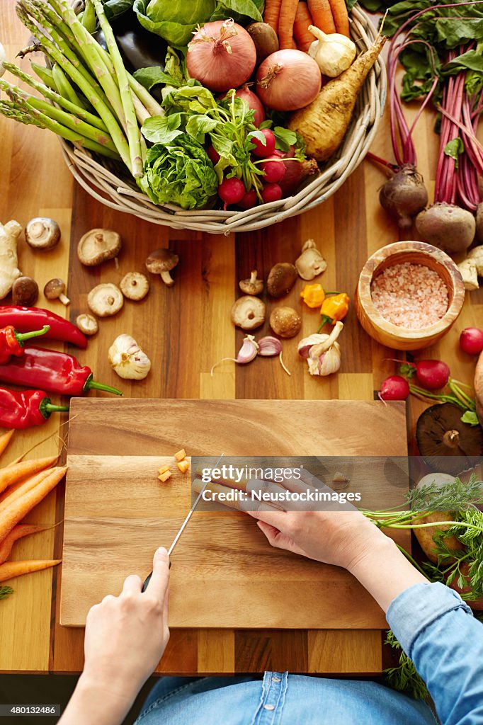 Woman cutting carrots on wooden board