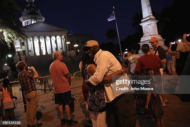 Couple embraces as the Confederate flag flies in front of the South Carolina statehouse on its last evening on July 9, 2015 in Columbia, South...