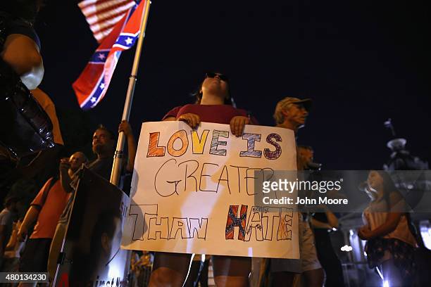 People demonstrate as the Confederate "Stars and Bars" flies in front of the South Carolina statehouse on its last evening on July 9, 2015 in...