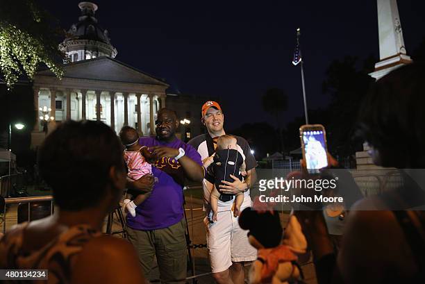 People pose for photos as the Confederate flag flies in front of the South Carolina statehouse on its last evening on July 9, 2015 in Columbia, South...