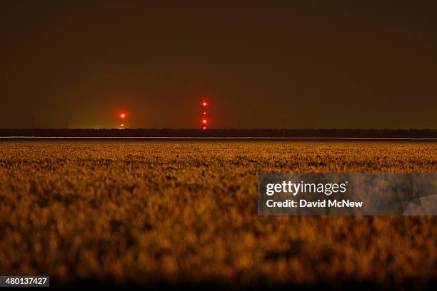 Farm is illuminated in the night with light from gas being flared as waste from the Monterey Shale formation where gas and oil extraction using...