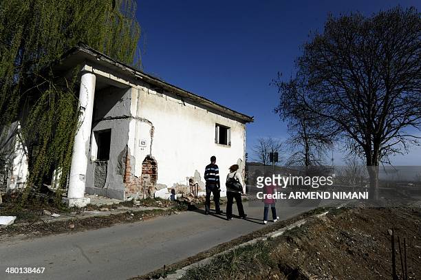 Pedestrians walk on March 22, 2014 past former Yugoslav army barracks, near the town of Mitrovica, which were destroyed during the 1999 NATO air...