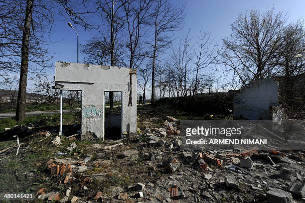 Kosovar boys walk on March 22, 2014 past former Yugoslav army barracks, near the town of Mitrovica, which were destroyed during the 1999 NATO air...