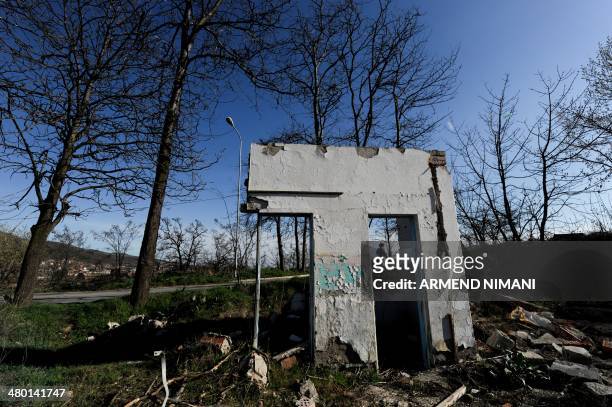 Kosovo Albanian woman walks on March 22, 2014 past former Yugoslav army barracks, near the town of Mitrovica, which were destroyed during the 1999...