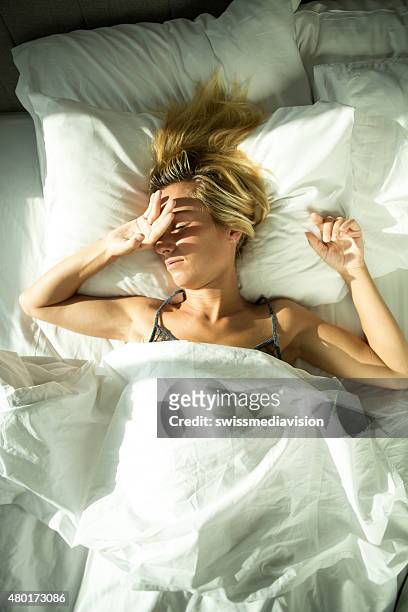 girl awaked by sunlight coming in hotel room - inconvenience stock pictures, royalty-free photos & images