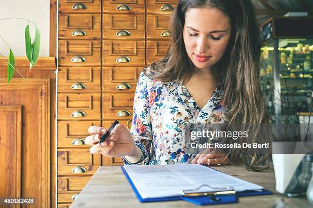 beautiful businesswoman signing contract in a cafe indoors - filling stockfoto's en -beelden