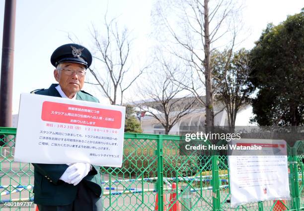 An elderly security guard, stands outside the fence not to allow supporters into the restricted area prior to the J.League match between Urawa Red...