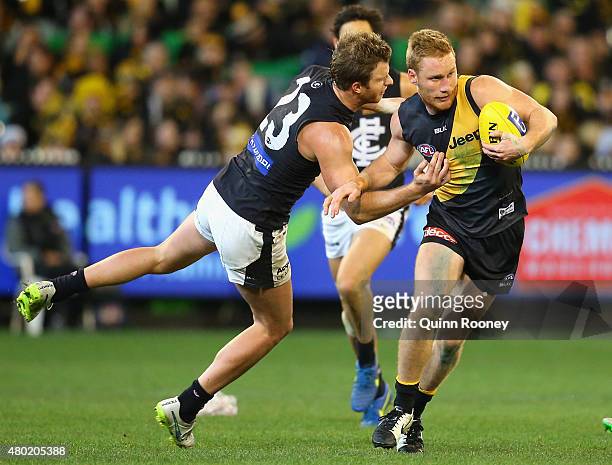 Nick Vlastuin of the Tigers fends off a tackle by Lachie Henderson of the Blues during the round 15 AFL match between the Richmond Tigers and the...
