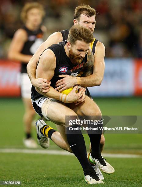 Zach Tuohy of the Blues is tackled by Kamdyn McIntosh of the Tigers during the 2015 AFL round 15 match between the Richmond Tigers and the Carlton...