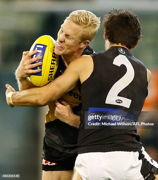 Steven Morris of the Tigers is tackled by Troy Menzel of the Blues during the 2015 AFL round 15 match between the Richmond Tigers and the Carlton...