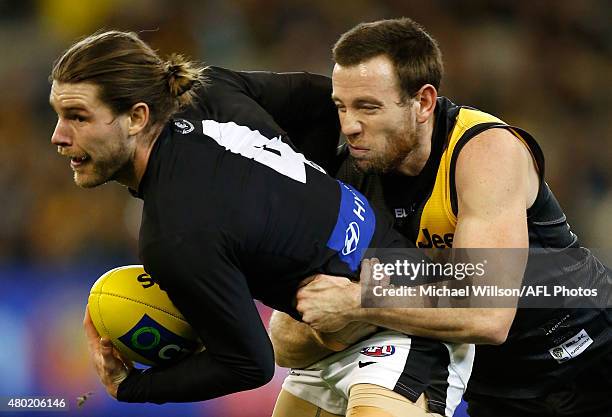 Bryce Gibbs of the Blues is tackled by Jake Batchelor of the Tigers during the 2015 AFL round 15 match between the Richmond Tigers and the Carlton...