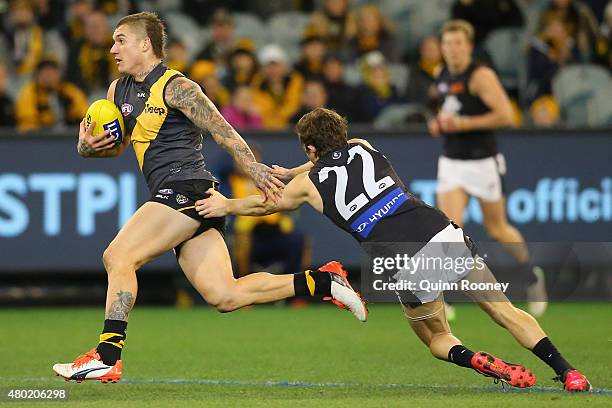 Dustin Martin of the Tigers fends off a tackle by Jason Tutt of the Blues during the round 15 AFL match between the Richmond Tigers and the Carlton...