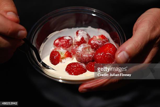 Spectator eats strawberries in the grounds of Wimbledon during day eleven of the Wimbledon Lawn Tennis Championships at the All England Lawn Tennis...