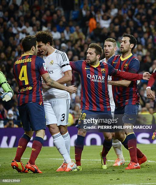 Barcelona's players react as Barcelona's midfielder Cesc Fabregas vies with Real Madrid's Portuguese defender Pepe during the Spanish league...